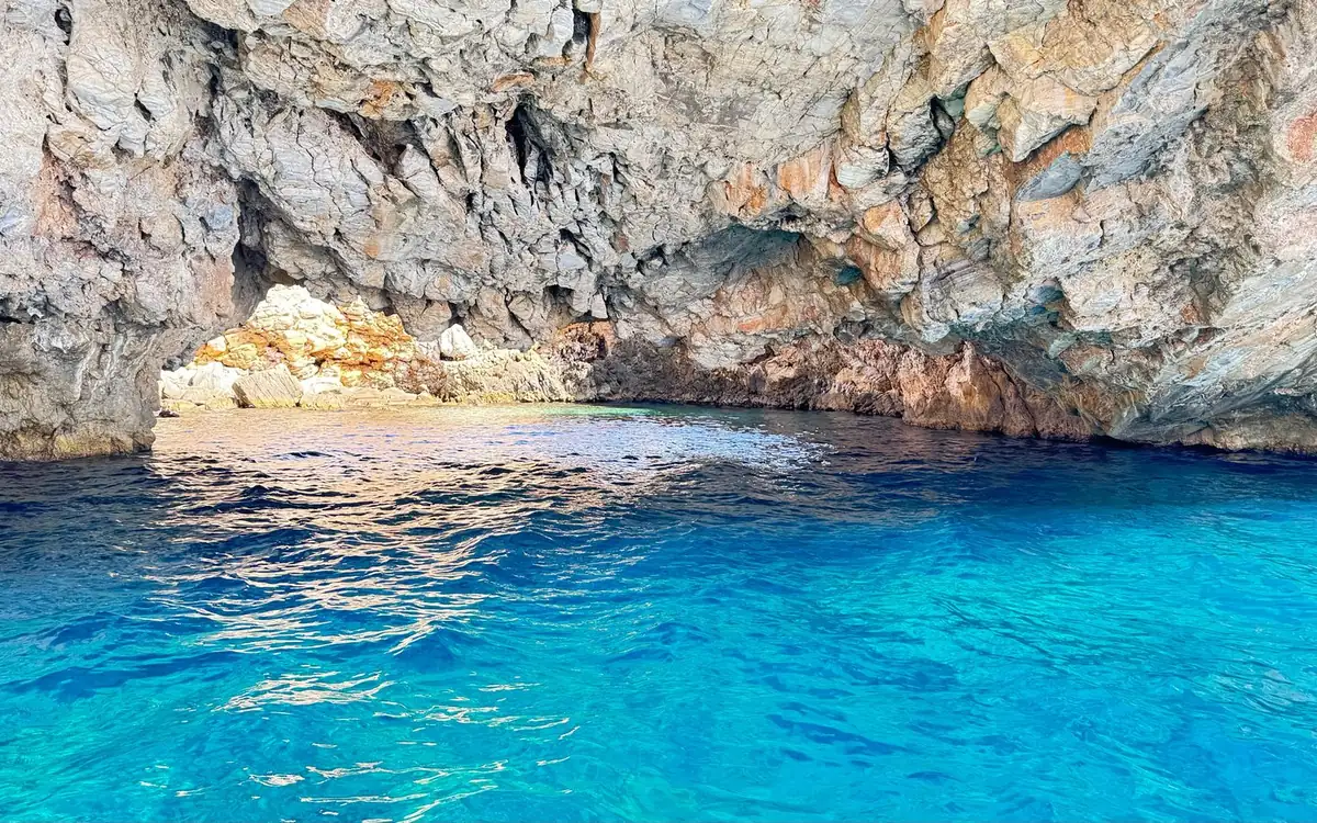 Inside a sea cave: a low rock roof over bright turquoise water