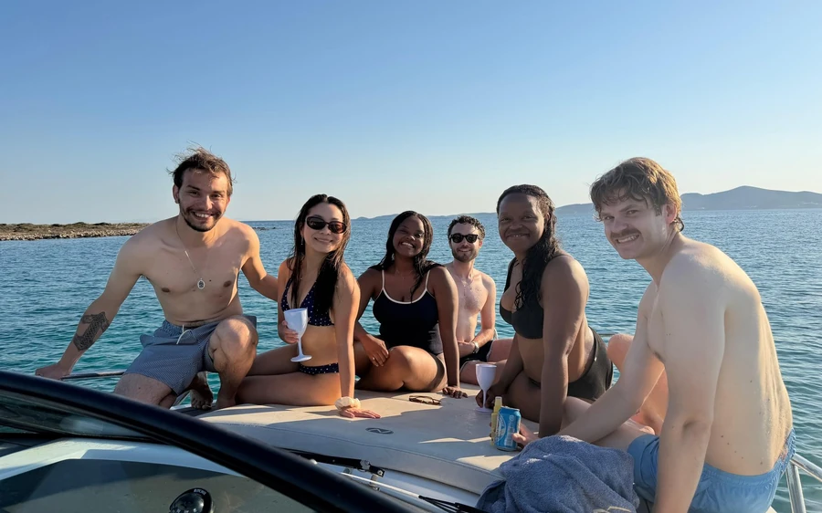 Six friends sitting on the bow of a speedboat out at sea