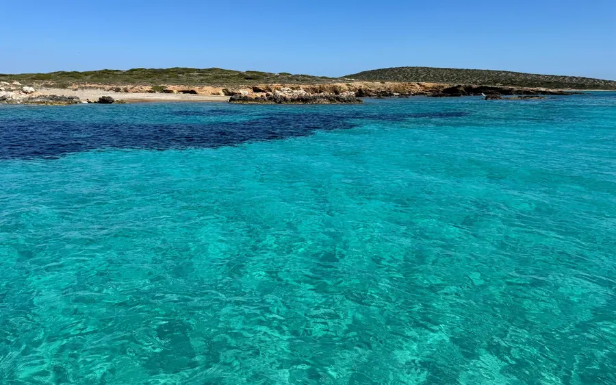 Clear turquoise shallows off a low, rocky island