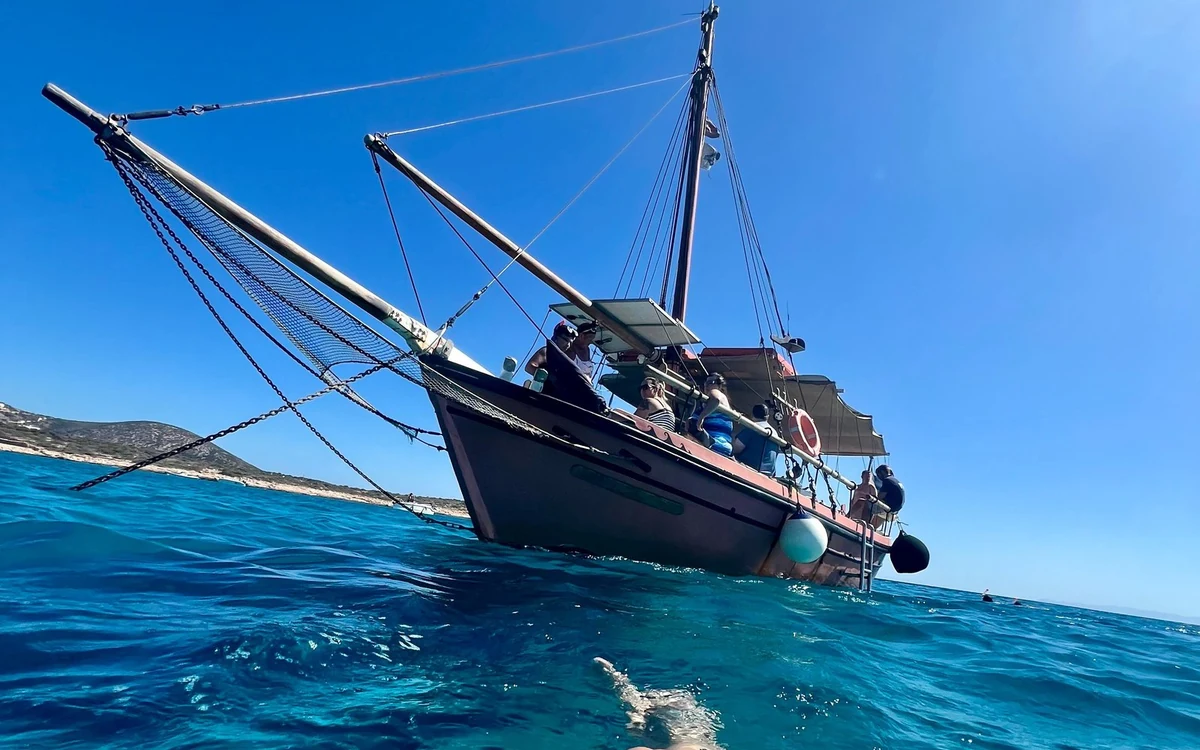 A traditional wooden boat in turquoise water off a low island